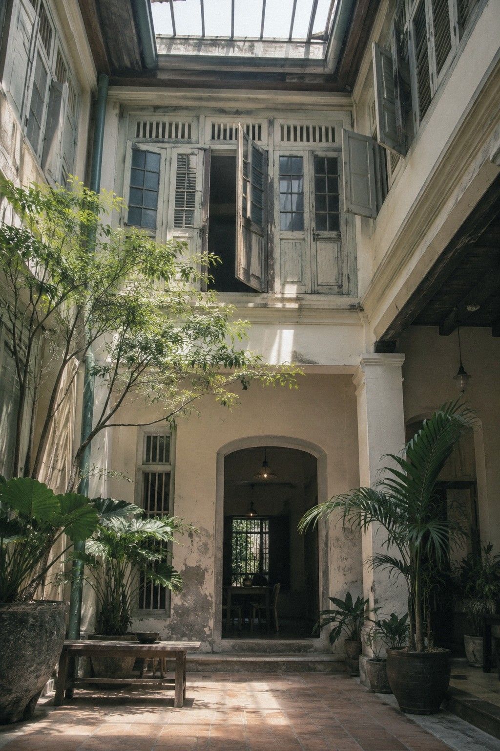 Inside the shophouse, daylight falls through the reopened airwell onto old timber beams and a tiled floor